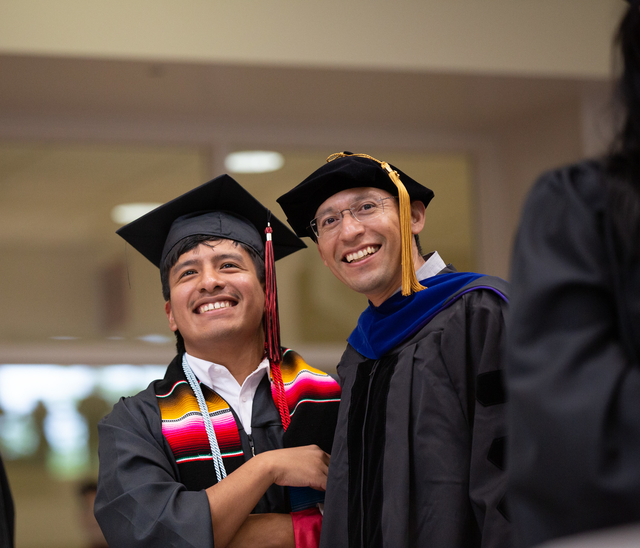 Student standing with his professor at hooding ceremony, smiling and happy