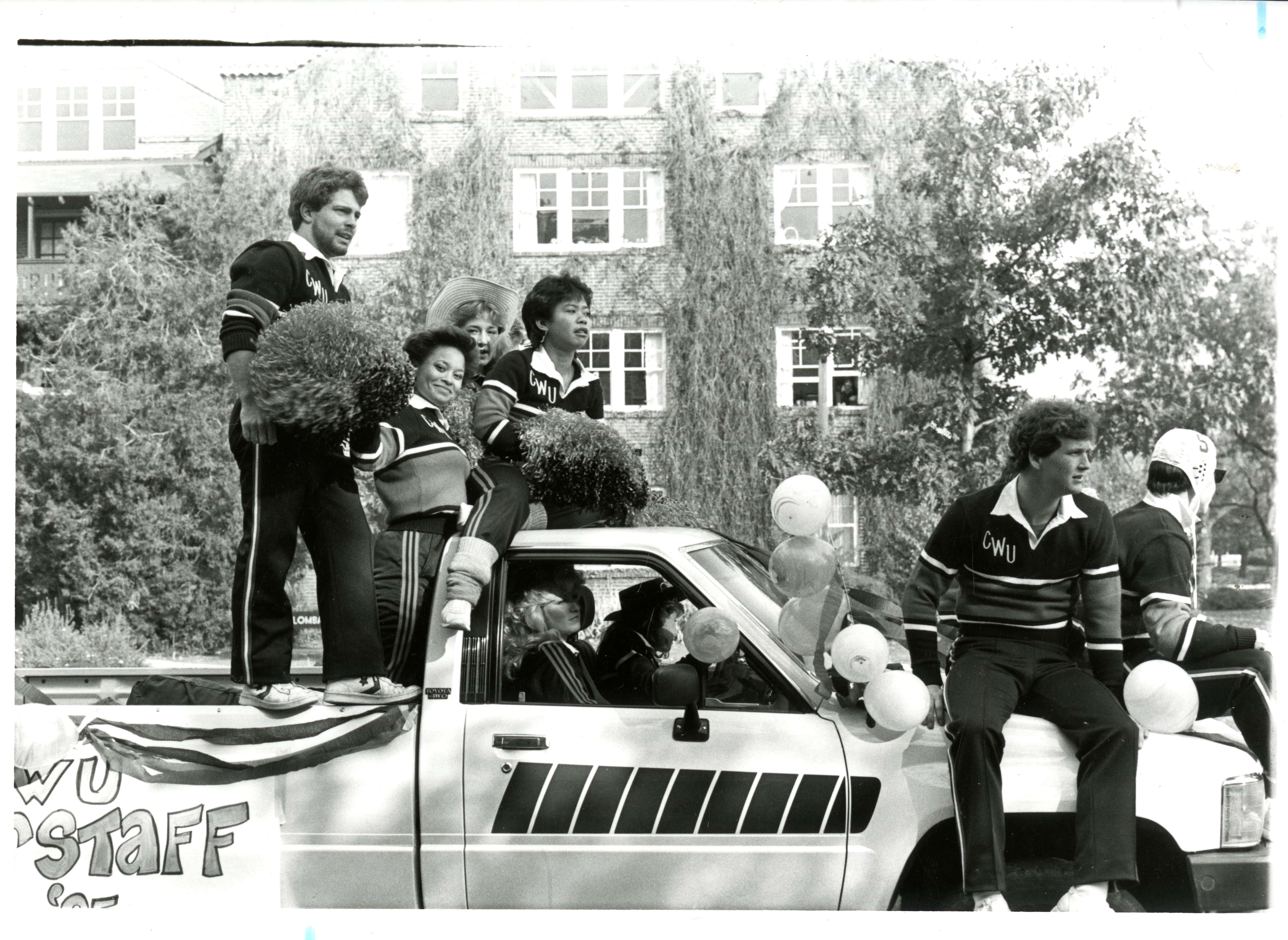 Black and White image of CWU students in and on a white truck in front of Sue Lombard Residence Hall.