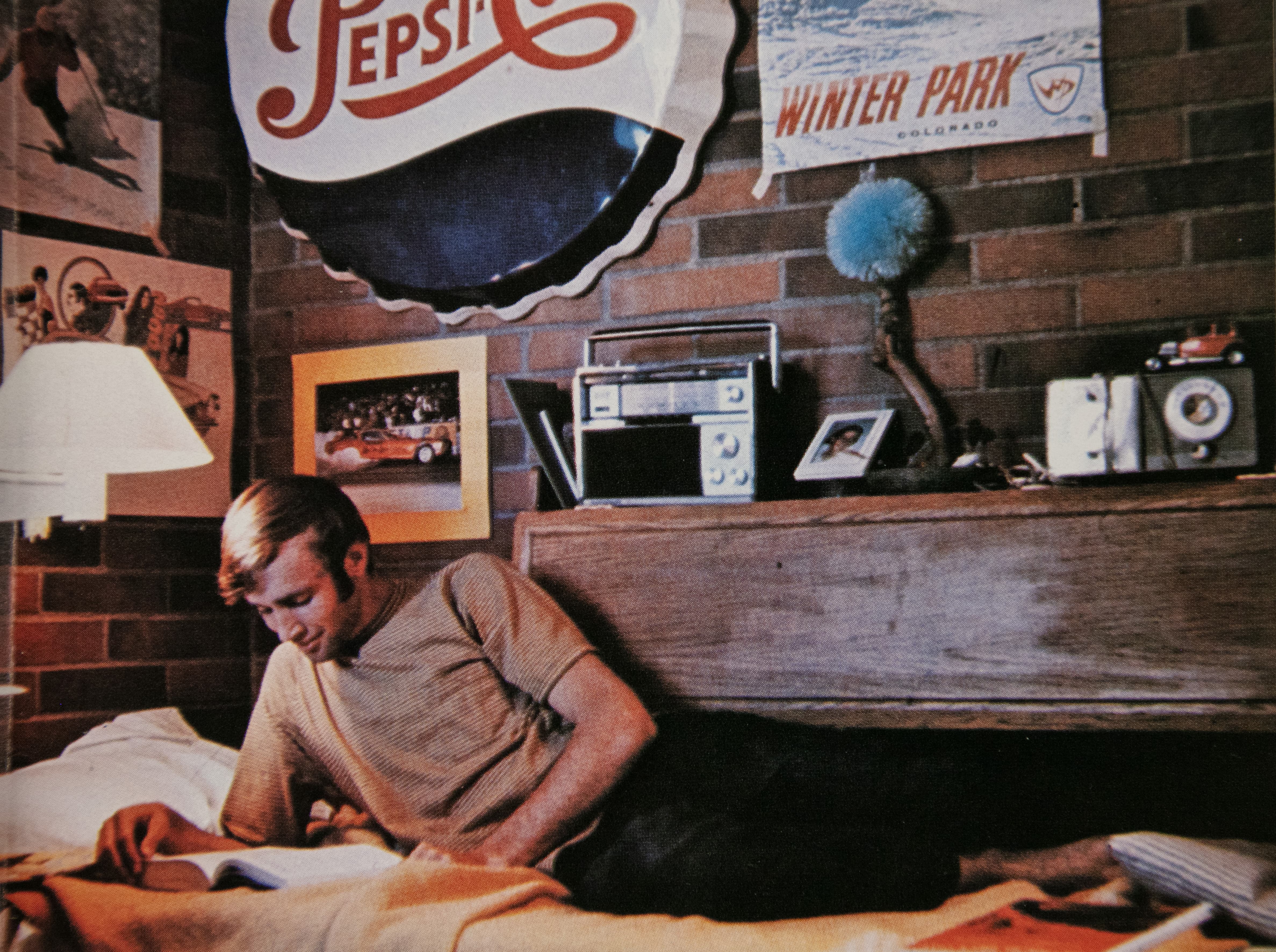 A retro style photo of a male student reading a book on his bed in his dorm.